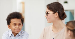 Child and teacher sitting at a table talking