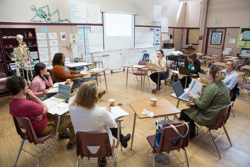 Teachers sitting at student desks talking